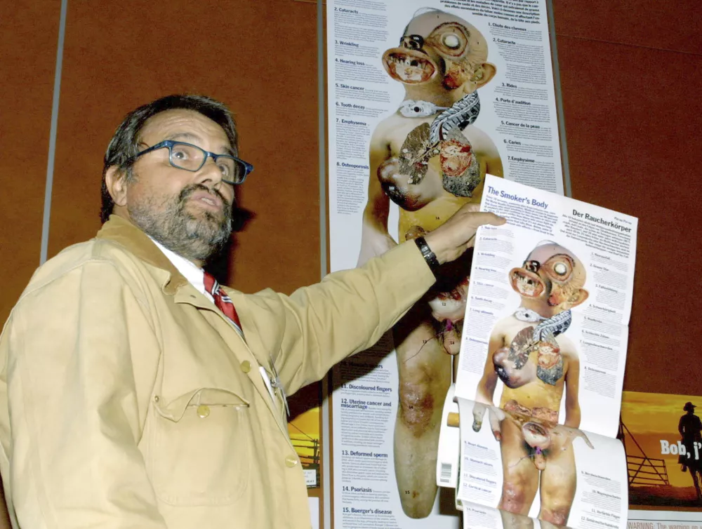 EDS NOTE: NUDITY - File - Italian photographer Oliviero Toscani holds a poster showing a "Smoker's Body" during a press conference on tobacco advertising, in Geneva, Switzerland, Thursday, March 21, 2002. (AP Photo/ Donald Stampfli, File)