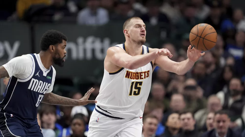 Denver Nuggets center Nikola Jokic makes a pass under pressure from Dallas Mavericks forward Naji Marshall (13) in the second half of an NBA basketball game in Dallas, Tuesday, Jan. 14, 2025. (AP Photo/Tony Gutierrez)