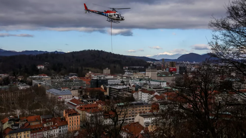 - Helikopter z privezanim drevesom in potniško letalo,- drevo v zraku, leteče drevo,- 13.01.2024. - Sečnja in spravilo oslabljenega lesa na Grajskem hribu v Ljubljani tudi s helikopterjem prvič v Sloveniji.//FOTO: Bojan Velikonja