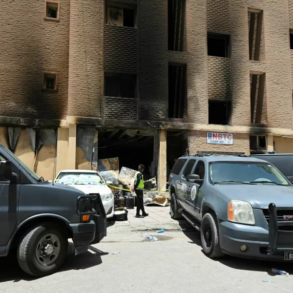 A Kuwaiti police officer is seen in front of a burnt building following a deadly fire, in Mangaf, southern Kuwait, June 12, 2024. REUTERS/Stringer