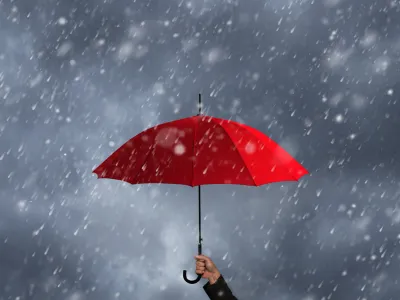 Red umbrella in the hands of businessmen amid a rainstorm.