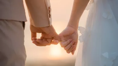 The bride and groom use the little finger together. lovely couple hold hand with sunset background