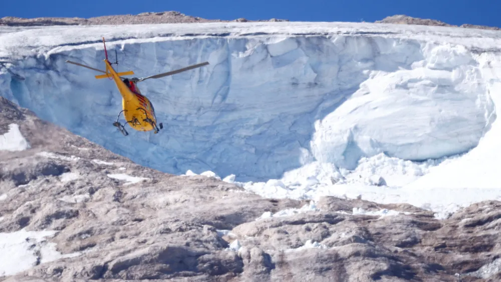 A helicopter participates in a search and rescue operation over the site of a deadly collapse of parts of a mountain glacier in the Italian Alps amid record temperatures, at Marmolada ridge, Italy July 6, 2022. REUTERS/Guglielmo Mangiapane ?