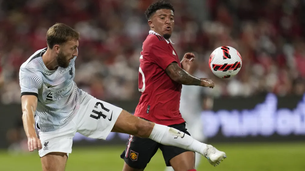 Liverpool's Nat Philips, left, fights for the ball with Manchester United's Jadon Sancho during their pre-season soccer match at Rajamangala national stadium in Bangkok, Tuesday, July 12, 2022. Manchester United beat Liverpool 4-0.(AP Photo/Sakchai Lalit)