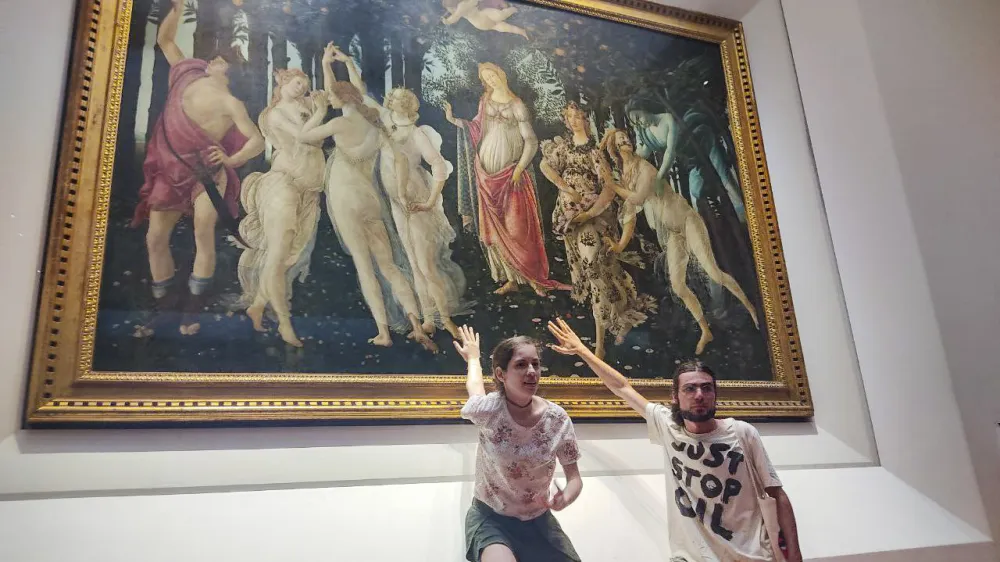 Two activists of Ultima Generazione (Last Generation) environmentalist group claim to glue themselves to the glass protecting Italian Renaissance painter Sandro Botticelli's Primavera (Spring) in Florence's Uffizi Galleries, central Italy, Friday, July 22, 2022. Carabinieri police said two Italian young women and a man sat on the floor in the Uffizi's Botticelli room and displayed a banner reading, "Last Generation No Gas No Coal". The museum said thanks to the glass the masterpiece was unharmed. (Ultima Generation via AP)(Ultima Generation via AP)