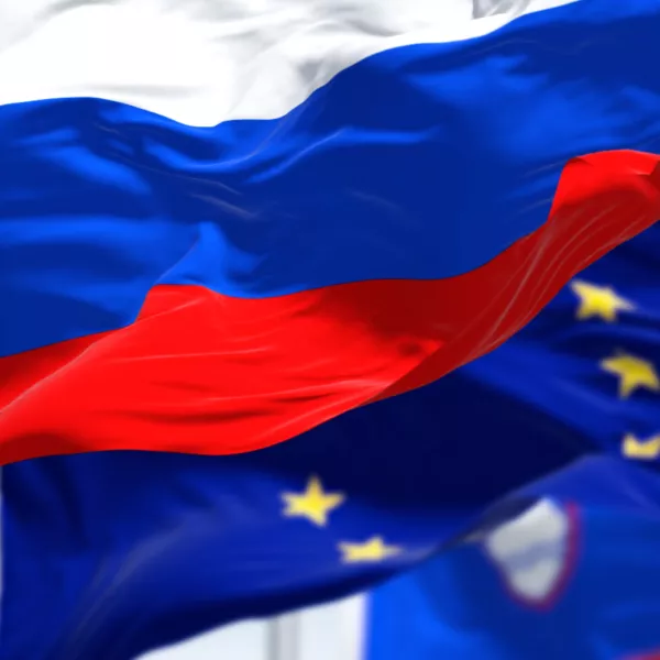 Detail of the national flag of Slovenia waving in the wind with blurred european union flag in the background on a clear day. Democracy and politics. European country. Selective focus.