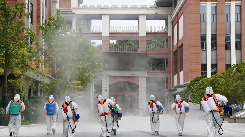 Workers in protective suits disinfect the compound of a primary school before schools reopen for the upcoming semester, following the coronavirus disease (COVID-19) outbreak in Wuhan, Hubei province, China August 25, 2021. China Daily via REUTERS ATTENTION EDITORS - THIS IMAGE WAS PROVIDED BY A THIRD PARTY. CHINA OUT.