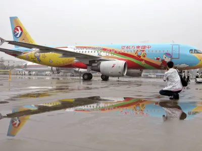 A man takes a picture in front of an Eastern China airplane which is sprayed with children's paintings at Hongqiao Airport in Shanghai, June 1, 2007. REUTERS/Aly Song (CHINA)