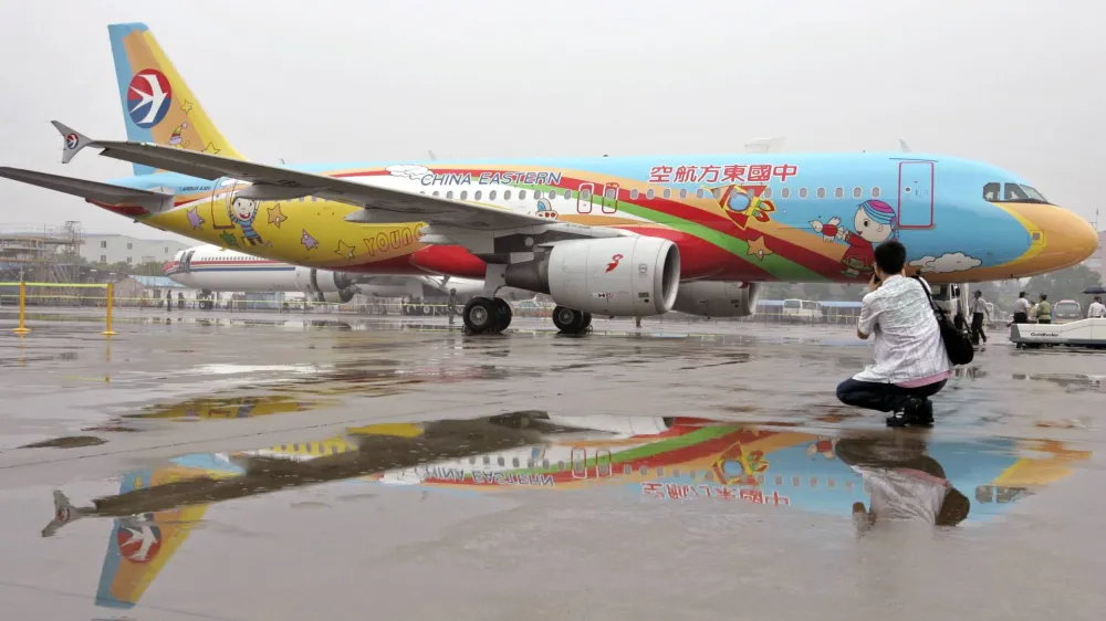 A man takes a picture in front of an Eastern China airplane which is sprayed with children's paintings at Hongqiao Airport in Shanghai, June 1, 2007. REUTERS/Aly Song (CHINA)