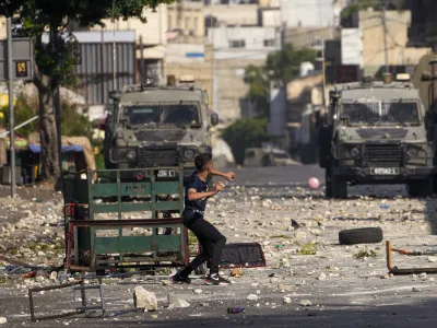 Palestinian demonstrators clash with the Israeli army while forces carry out an operation in the West Bank town of Nablus, Tuesday, Aug. 9, 2022. Israeli police said forces encircled the home of Ibrahim al-Nabulsi, who they say was wanted for a string of shootings in the West Bank earlier this year. They said al-Nabulsi and another Palestinian militant were killed in a shootout at the scene, and that troops found arms and explosives in his home. (AP Photo/Majdi Mohammed)