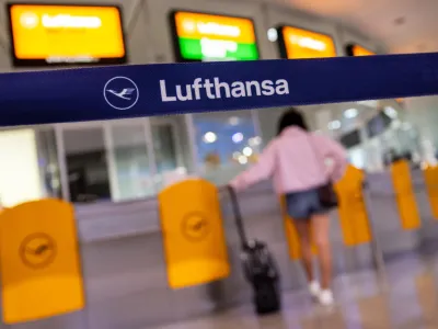 27 July 2022, Bavaria, Munich: A passenger waits at a Lufthansa service counter at Munich Airport. German services trade union Verdi is calling out ground staff at Munich airport on a token strike next week in support of demands for a considerable pay rise, following a successful strike by Lufthansa ground staff two weeks ago. Photo: Peter Kneffel/dpa