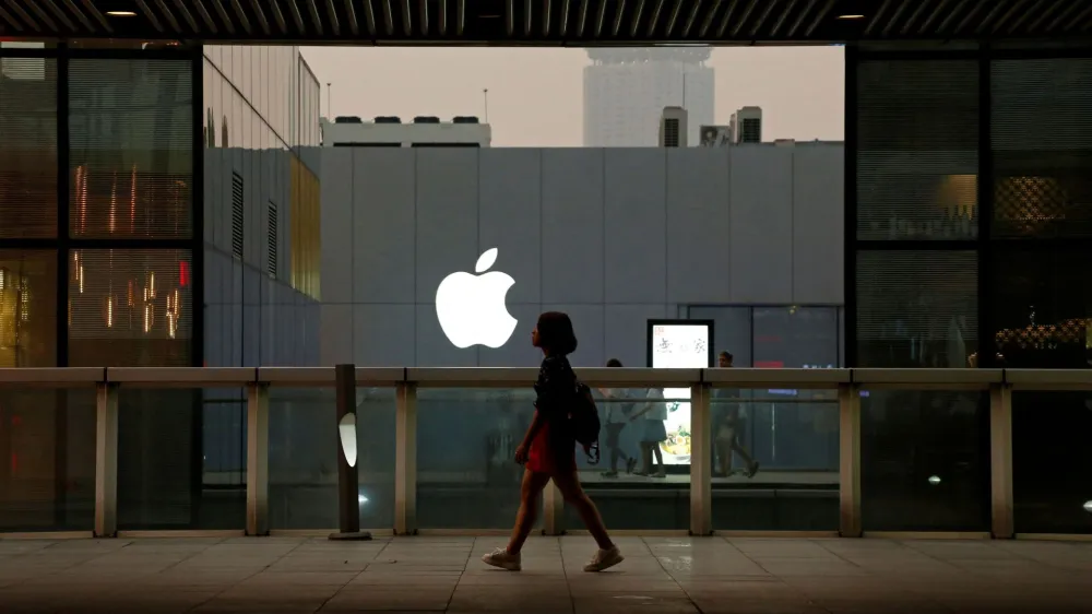 FILE PHOTO: A woman walks past an Apple store in Beijing, China July 28, 2016. REUTERS/Thomas Peter/File Photo