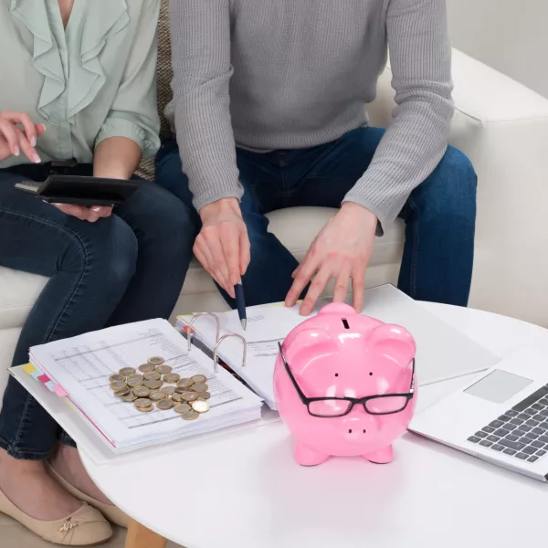 ﻿Close-up Of Couple Sitting On Sofa Calculating Bills At Home