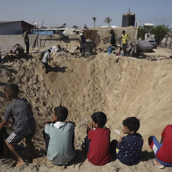 Palestinian children sit at the edge of a crater after an Israeli airstrike in Khan Younis, southern Gaza Strip, Friday, June 21, 2024. (AP Photo /Jehad Alshrafi)