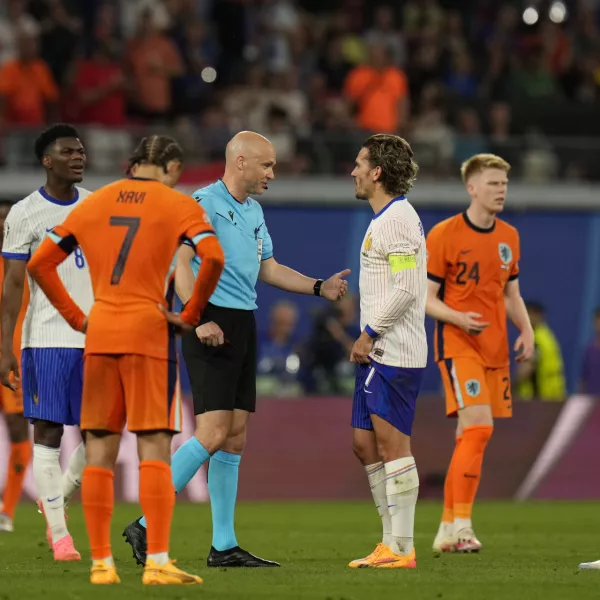 Referee Anthony Taylor is surrounded by players as he waits for a fourth official decision on a goal by Xavi Simons of the Netherlands that was then disallowed for offside during the Group D match between the Netherlands and France at the Euro 2024 soccer tournament in Leipzig, Germany, Friday, June 21, 2024. (AP Photo/Hassan Ammar)