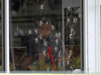 Damage can be seen to a front window law enforcement officers work the scene of a shooting at the Mad Butcher grocery store in Fordyce, Ark., Friday, June 21, 2024. (Colin Murphey/Arkansas Democrat-Gazette via AP)