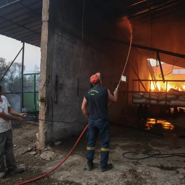 A firefighter works to extinguish the flames in a burning building as a wildfire burns in the village of Kalfas, in southern Greece, June 21, 2024. REUTERS/Giorgos Moutafis