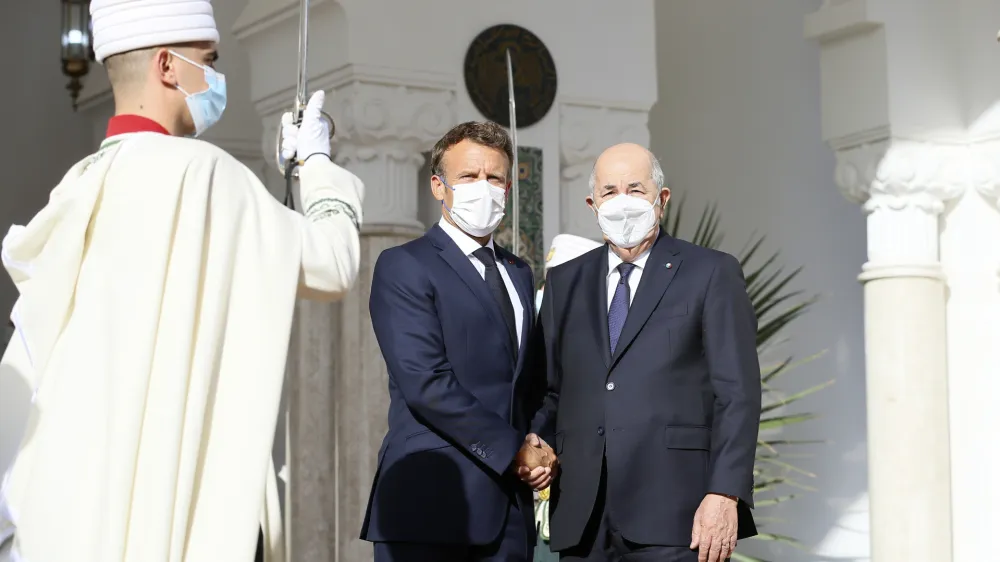 French President Emmanuel Macron, center, shakes hands with Algerian President Abdelmajid Tebboune, Thursday, Aug. 25, 2022 in Algiers. French President Emmanuel Macron is in Algeria for a three-day official visit aimed at addressing two major challenges: boosting future economic relations while seeking to heal wounds inherited from the colonial era, 60 years after the North African country won its independence from France. (AP Photo/Anis Belghoul)