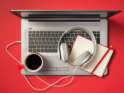 Above photo of grey laptop cup of coffee notebook with pencil and headphones isolated on the red backdrop