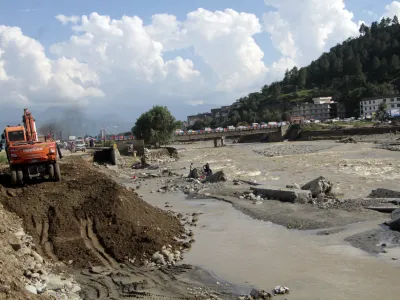 Local authorities use heavy machinery to rebuild a damaged road after a flood-affected area, in Swat valley, Pakistan, Sunday, Aug. 28, 2022. International aid for flood victims have started arriving in Pakistan, as military helicopters, troops and rescuers resumed operations early Monday to evacuate marooned people and deliver much-needed food after the deluge killed over 1,000 since mid-June. (AP Photo/Naveed Ali)