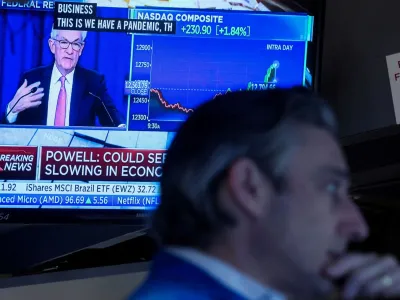 FILE PHOTO: A trader works, as Federal Reserve Chair Jerome Powell is seen delivering remarks on a screen, on the floor of the New York Stock Exchange (NYSE) in New York City, U.S. May 4, 2022. REUTERS/Brendan McDermid/File Photo