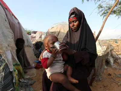 FILE PHOTO: Rukia Nur feeds her child outside her makeshift dwelling after fleeing famine in the Marka Lower Shebbele regions to the capital Mogadishu, September 20, 2014. The United Nations said this month more than a million people in war-ravaged Somalia were struggling to meet daily nutritional needs. The roughly 130,000 people displaced from their homes this year alone are bearing the brunt of the crisis. REUTERS/Feisal Omar (SOMALIA - Tags: DISASTER SOCIETY POVERTY CIVIL UNREST)/File Photo