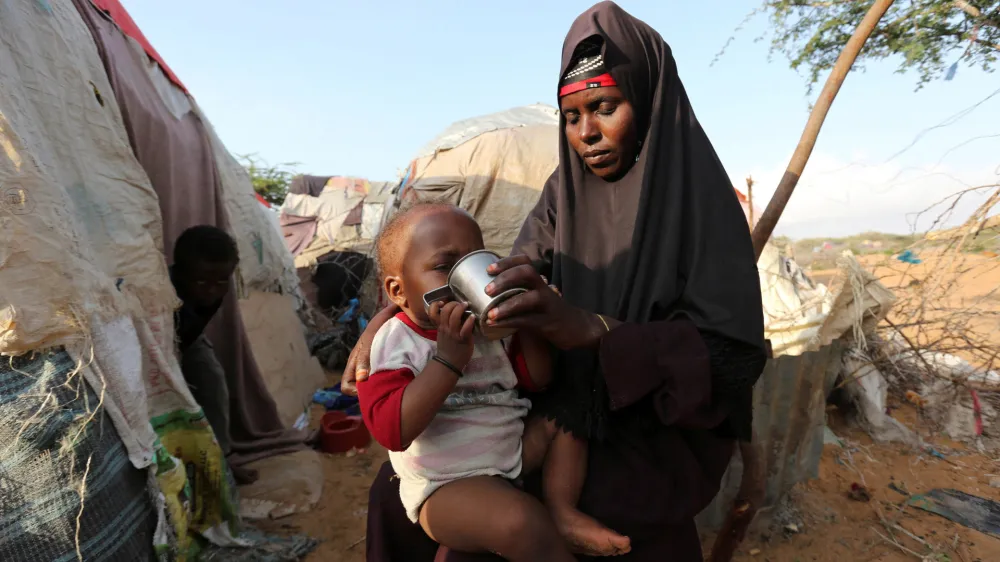 FILE PHOTO: Rukia Nur feeds her child outside her makeshift dwelling after fleeing famine in the Marka Lower Shebbele regions to the capital Mogadishu, September 20, 2014. The United Nations said this month more than a million people in war-ravaged Somalia were struggling to meet daily nutritional needs. The roughly 130,000 people displaced from their homes this year alone are bearing the brunt of the crisis. REUTERS/Feisal Omar (SOMALIA - Tags: DISASTER SOCIETY POVERTY CIVIL UNREST)/File Photo