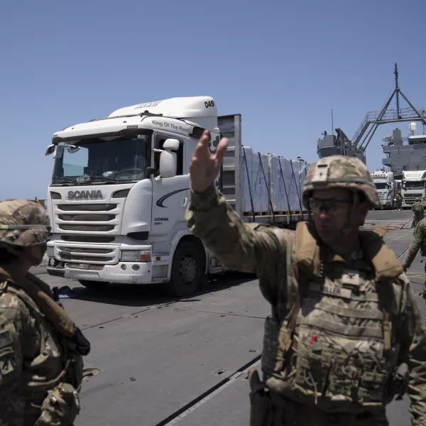 A U.S. Army soldier gestures as trucks loaded with humanitarian aid arrive at the U.S.-built floating pier Trident before reaching the beach on the coast of the Gaza Strip, Tuesday, June 25, 2024. (AP Photo/Leo Correa)