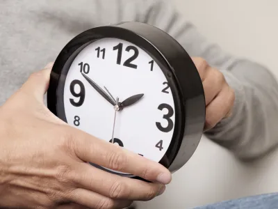 closeup of a young caucasian man adjusting the time of a clock