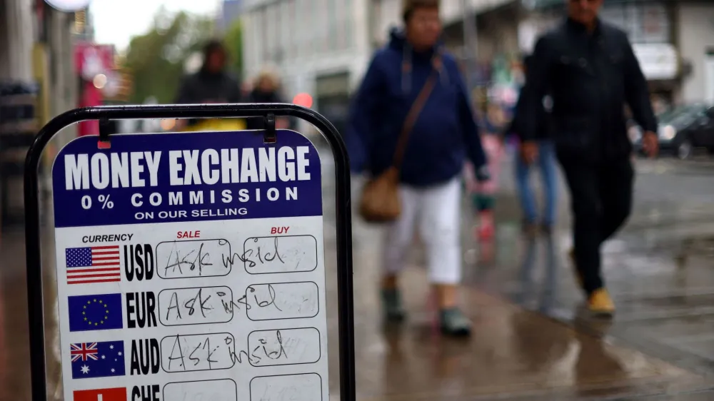 People walk past signage outside a currency exchange office in London, Britain, September 27, 2022. REUTERS/Hannah McKay