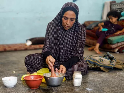 A displaced Palestinian woman prepares food at a school classroom where she shelters, amid food scarcity, as Israel-Hamas conflict continues, in Khan Younis in the southern Gaza Strip, June 26, 2024. REUTERS/Mohammed Salem