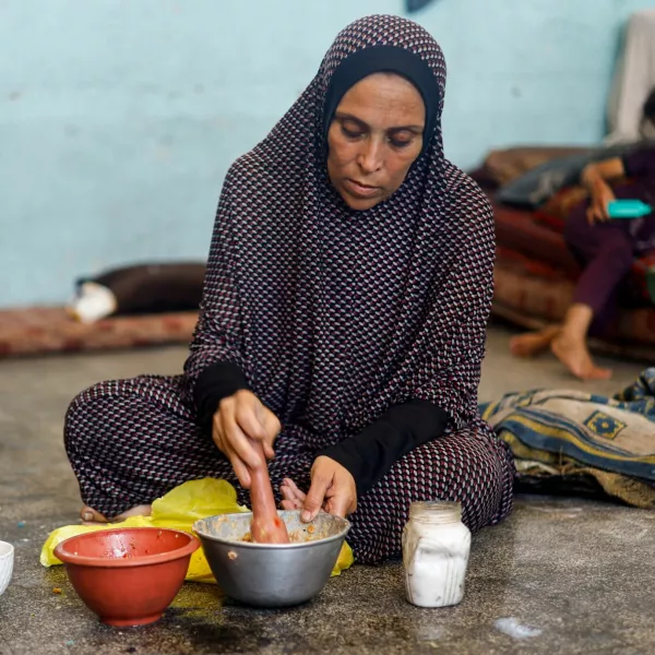 A displaced Palestinian woman prepares food at a school classroom where she shelters, amid food scarcity, as Israel-Hamas conflict continues, in Khan Younis in the southern Gaza Strip, June 26, 2024. REUTERS/Mohammed Salem