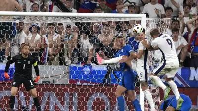 England's Harry Kane, right, attempts to head in the ball as Slovenia's goalkeeper Jan Oblak, left, defends as Slovenia's Jaka Bijol, second from left, and England's John Stones watch during a Group C match between the England and Slovenia at the Euro 2024 soccer tournament in Cologne, Germany, Tuesday, June 25, 2024. (AP Photo/Frank Augstein)