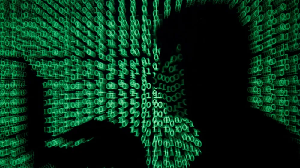 FILE PHOTO: A man holds a laptop computer as cyber code is projected on him in this illustration picture taken on May 13, 2017. REUTERS/Kacper Pempel/Illustration/File Photo