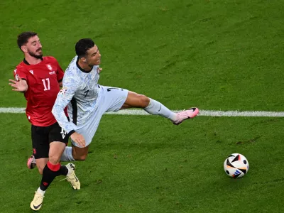 26 June 2024, North Rhine-Westphalia, Gelsenkirchen: Portugal's Cristiano Ronaldo (R) and Georgia's Otar Kiteishwili (L) fight for the ball during the UEFA Euro 2024 Group F soccer match between Georgia and Portugal at Arena auf Schalke. Photo: Bernd Thissen/dpa