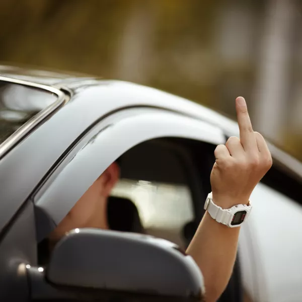 young driver shows middle finger, natural light, selective focus