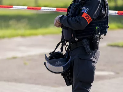 27 June 2024, Thuringia, Erfurt: A police officer stands in front of a police cordon near the suspected crime scene in Erfurt, where a man was shot dead. A large-scale police operation is currently underway. Photo: Jacob Schröter/dpa