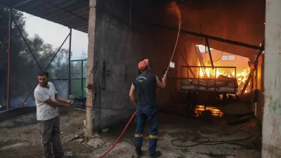 A firefighter works to extinguish the flames in a burning building as a wildfire burns in the village of Kalfas, in southern Greece, June 21, 2024. REUTERS/Giorgos Moutafis