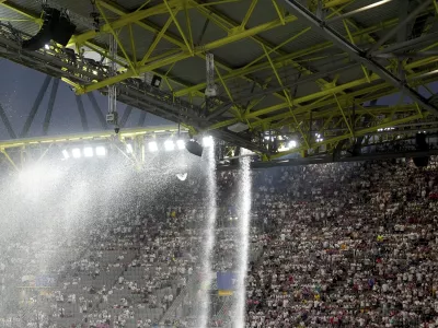 Rainwater flows from the stadium roof at a Round of 16 match between Germany and Denmark at the Euro 2024 soccer championship Saturday, June 29, 2024, in Dortmund, Germany. (Marcus Brandt/dpa via AP)