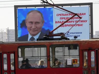 People look through the tram windows as they pass a big screen showing Russian President Vladimir Putin and reading: "Happy birthday to President Vladimir Putin from the Serb brethren!", in Belgrade, Serbia, Friday, Oct. 7, 2022. The posters are signed by a Pro-Russian right-wing group. Putin remains popular in Serbia despite the attack on Ukraine, and many in the Balkan country believe that the Russian president was provoked by the West into launching the invasion. (AP Photo/Darko Vojinovic)