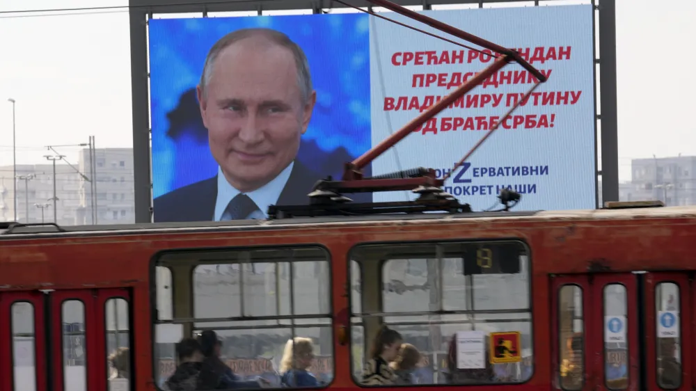 People look through the tram windows as they pass a big screen showing Russian President Vladimir Putin and reading: "Happy birthday to President Vladimir Putin from the Serb brethren!", in Belgrade, Serbia, Friday, Oct. 7, 2022. The posters are signed by a Pro-Russian right-wing group. Putin remains popular in Serbia despite the attack on Ukraine, and many in the Balkan country believe that the Russian president was provoked by the West into launching the invasion. (AP Photo/Darko Vojinovic)