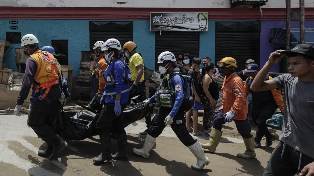 10 October 2022, Venezuela, Las Tejerias: Search and rescue workers carry the lifeless body of a woman after floods and a landslide caused by the storm 'Julia'. According to official figures, a total of at least 59 people died in Central and South America as a result of storms and floods. Photo: Jesus Vargas/dpa