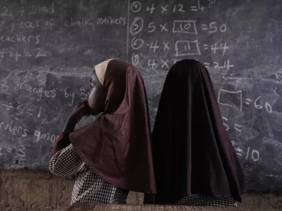 Students of Excellent Moral School attempt to answer a mathematics question on a blackboard inside a dimly lit classroom in Ibadan, Nigeria, Tuesday, May 28, 2024. Schools like Excellent Moral operate in darkness due to zero grid access, depriving students of essential tools like computers. (AP Photo/Sunday Alamba)