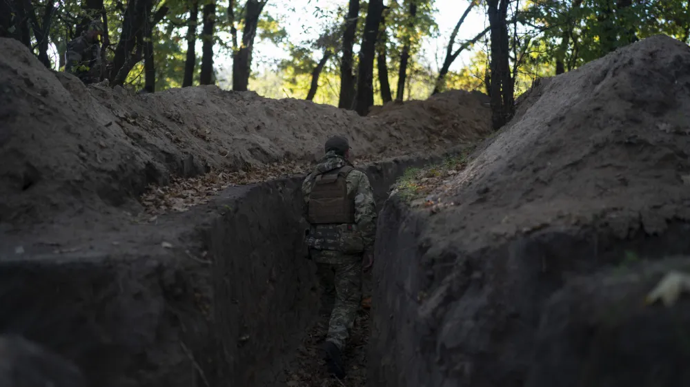 A Ukrainian serviceman checks the trenches dug by Russian soldiers in a retaken area in Kherson region, Ukraine, Wednesday, Oct. 12, 2022. (AP Photo/Leo Correa)