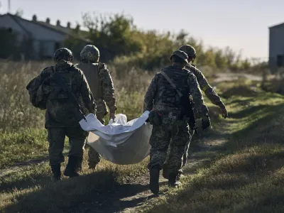 Ukrainian servicemen carry an exhumed body in the recently retaken village of Shandryholove, the Donetsk region, Ukraine, Sunday, Oct. 16, 2022. (AP Photo/LIBKOS)