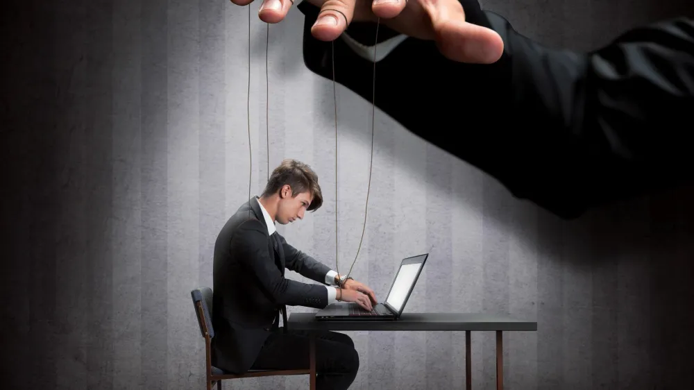 Businessman's hand controlling a worker marionette