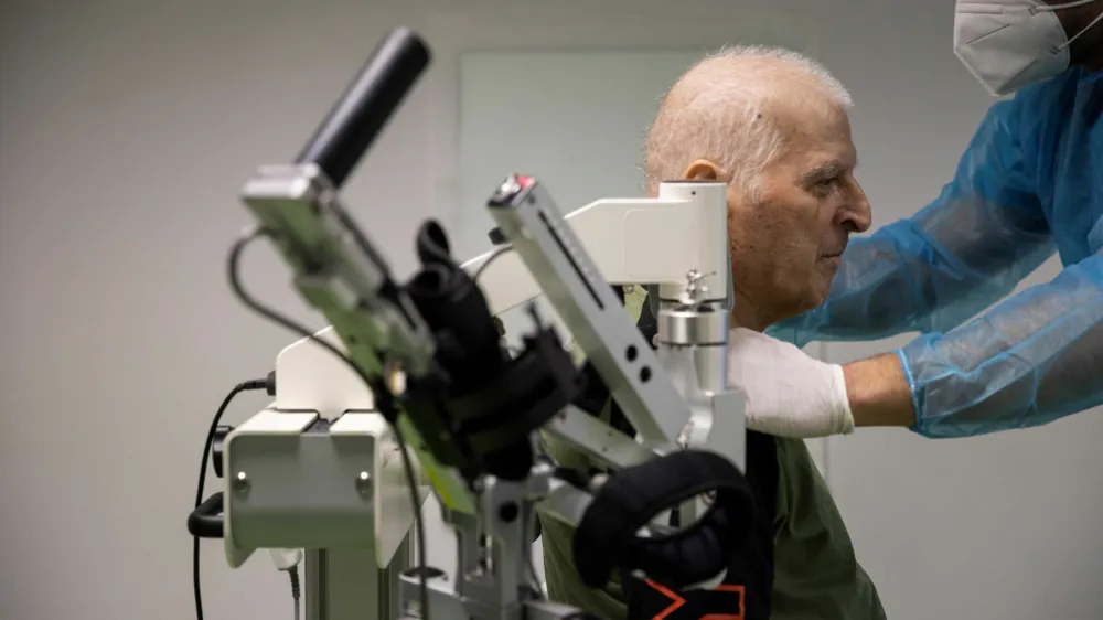 Yannis Ieremias, 70, is assisted to sit on a robotic-assisted hand therapy device at the Theseus Rehabilitation Centre in Athens, Greece, February 1, 2021. Ieremias, who spend more than 50 days in the intensive care unit of an Athens hospital with the coronavirus disease (COVID-19), must undergo therapy to recover from mobility problems caused by his extend hospitalisation. Picture taken February 1, 2021. REUTERS/Alkis Konstantinidis