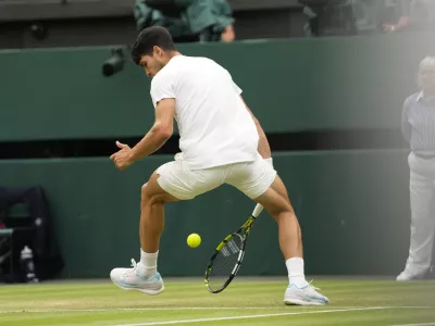 Spain's Carlos Alcaraz plays a shot back between his legs back to Francis Tiafoe of the United States during their third round match at the Wimbledon tennis championships in London, Friday, July 5, 2024. (AP Photo/Alberto Pezzali)