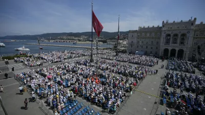 People attend a mass presided over by Pope Francis in Trieste's monumental square Piazza dell'Unita' d'Italia, in northern Italy, Sunday, July 7, 2024. The pope is in Trieste for a one-day visit. (AP Photo/Alessandra Tarantino)