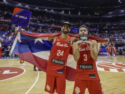 Puerto Rico's Jordan Howard, right, and Gian Clavell celebrate after their team qualified for the Paris 2024 Olympics, after eliminating Lithuania in a FIBA Olympic Qualifying basketball final in San Juan, Puerto Rico, Sunday, July 7, 2024. (AP Photo/Alejandro Granadillo)